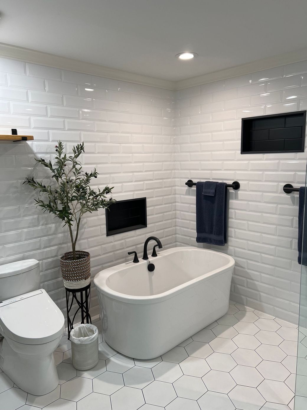 A bathroom with a bathtub , toilet , and plant.