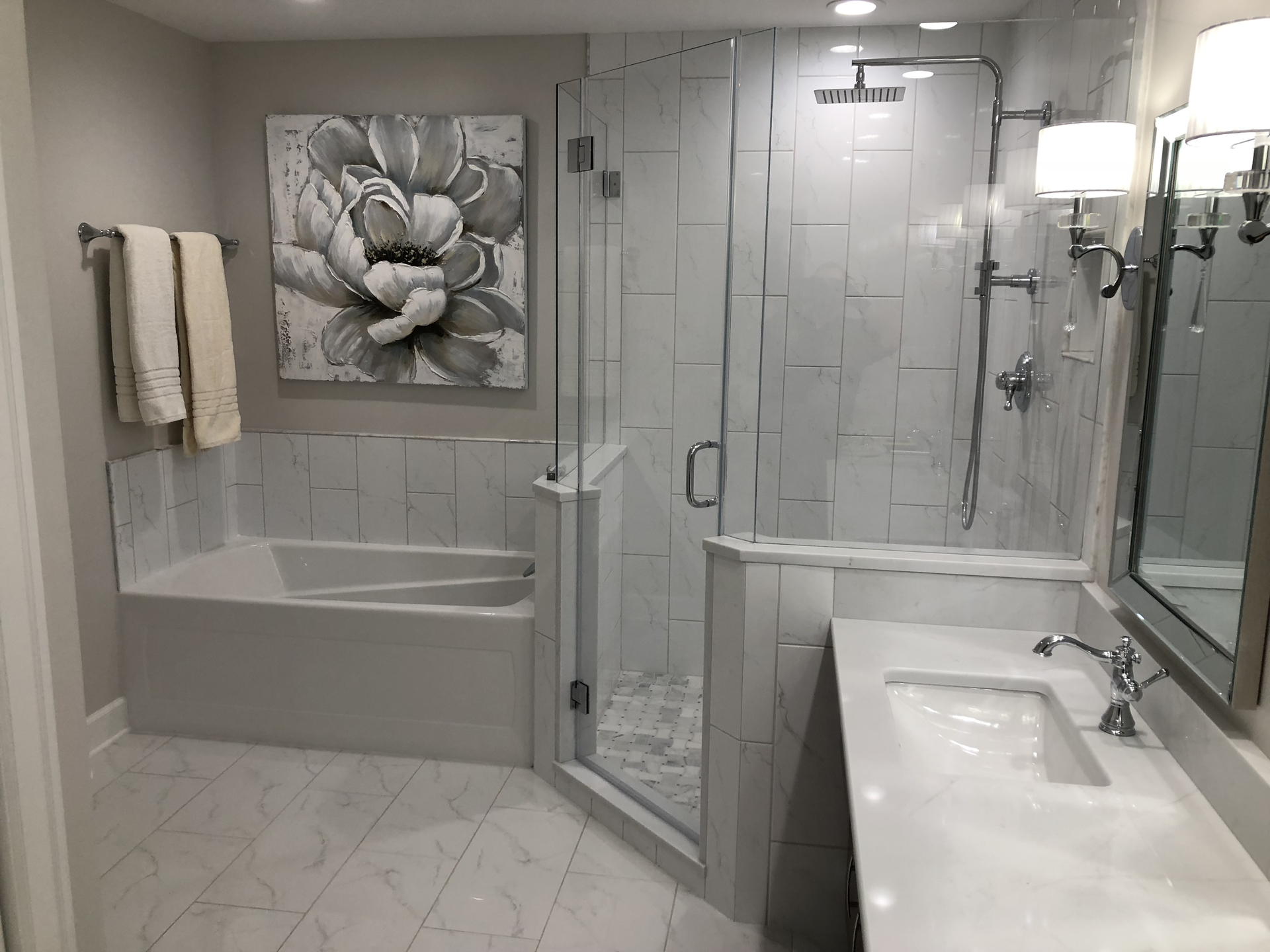 A bathroom with a tub , sink , mirror and shower.