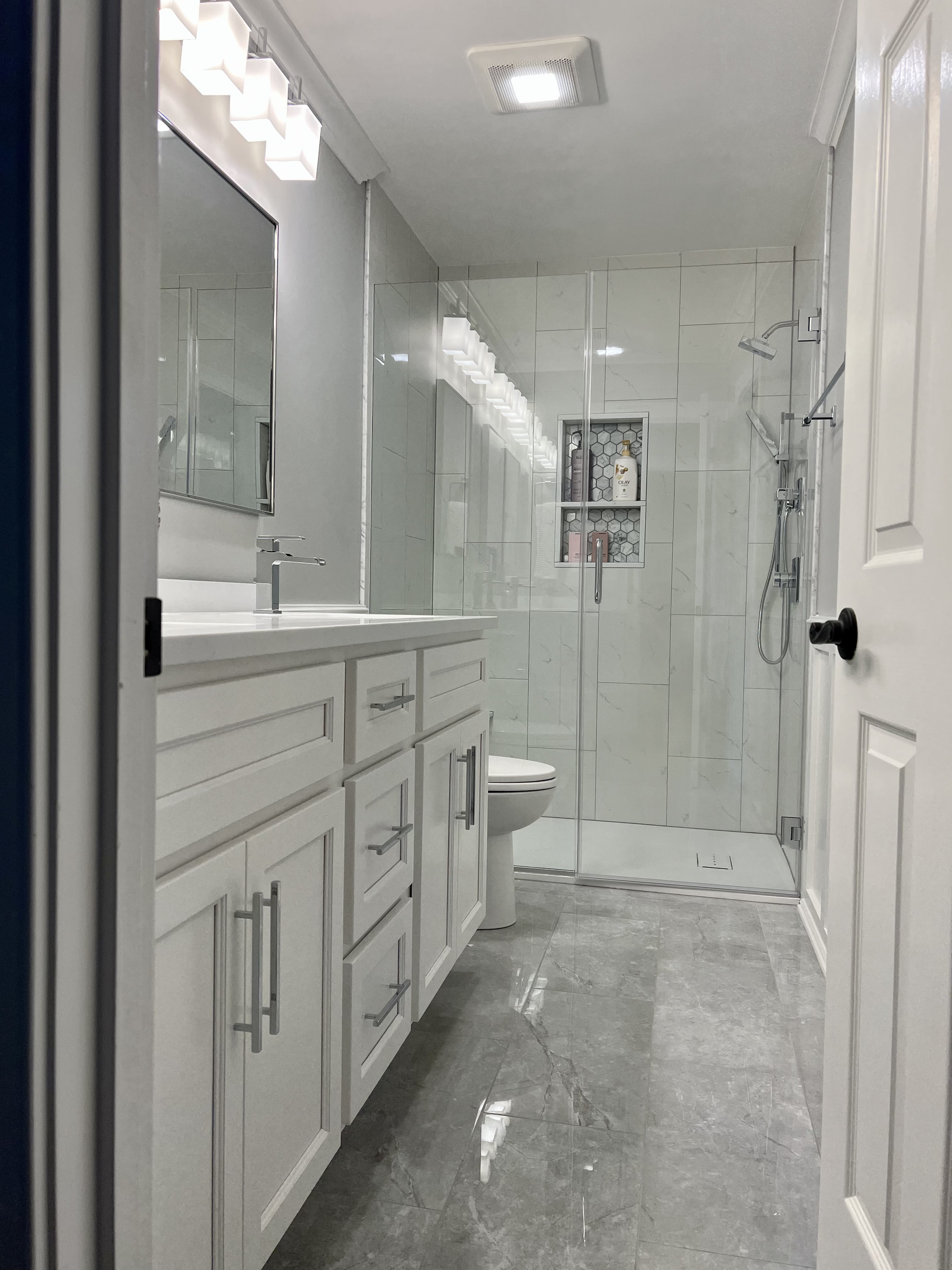 A bathroom with a toilet , sink , mirror and shower.
