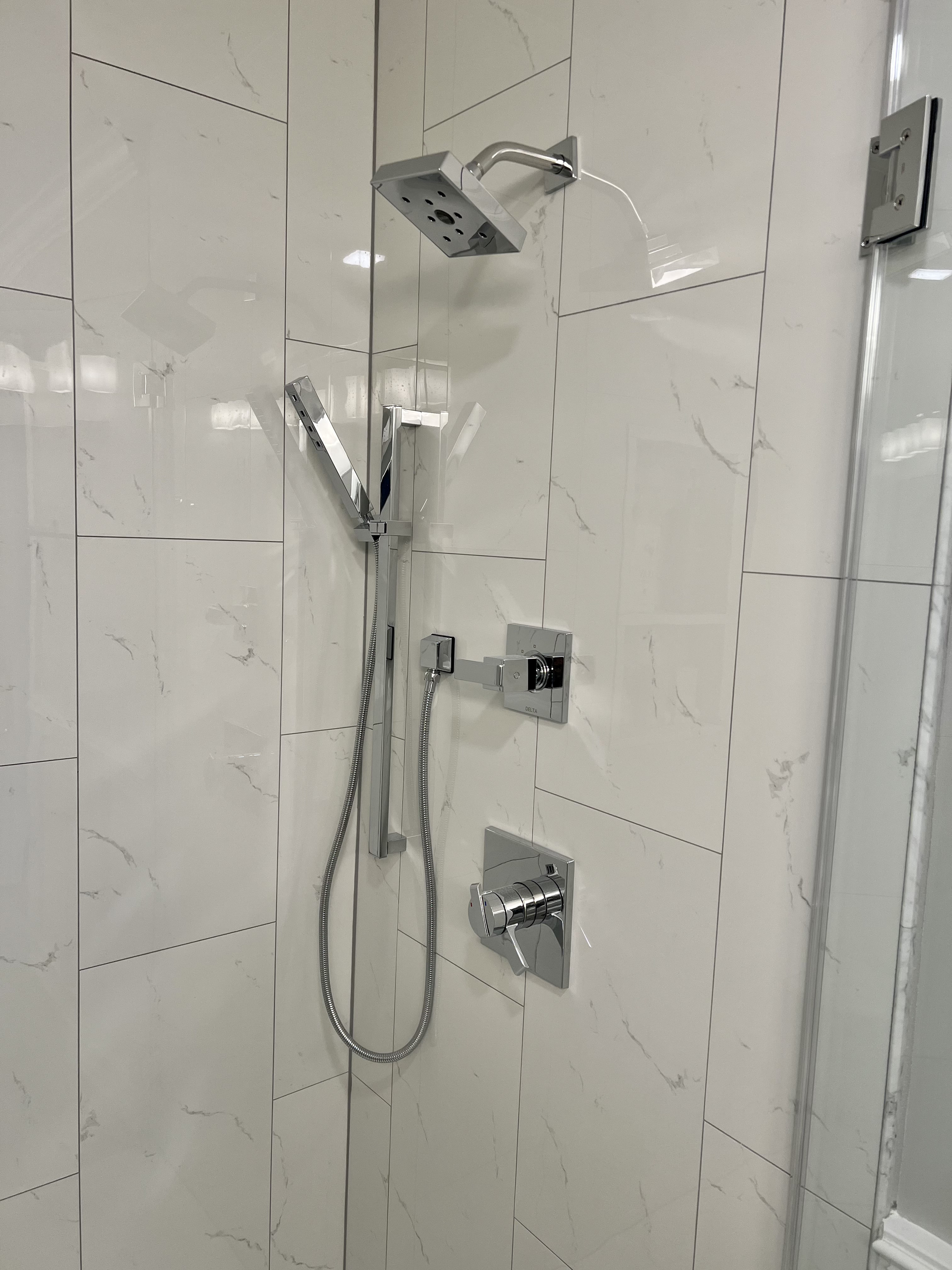 A shower with a shower head and a hose attached to it.