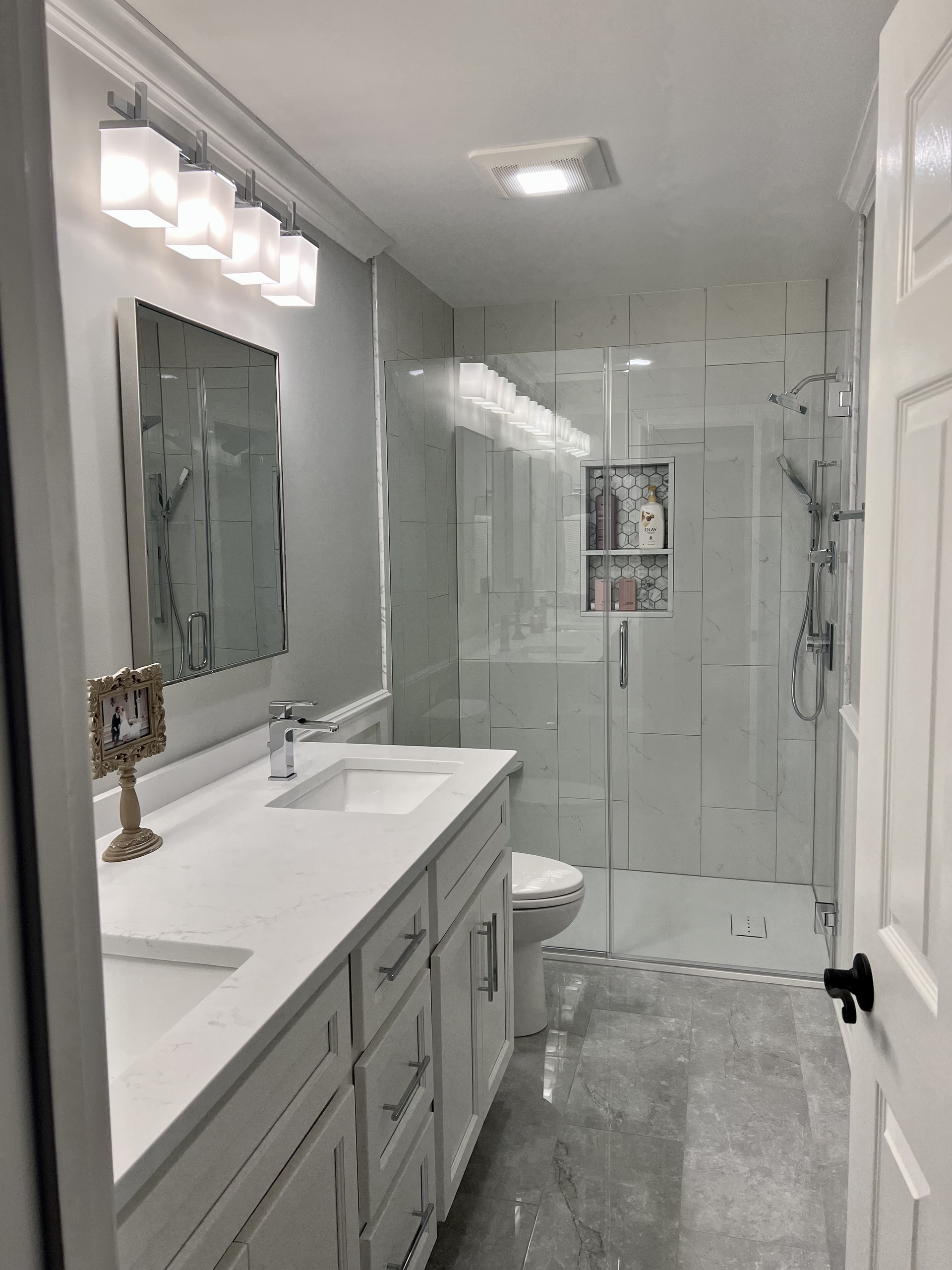 A bathroom with a sink , toilet , shower and mirror.