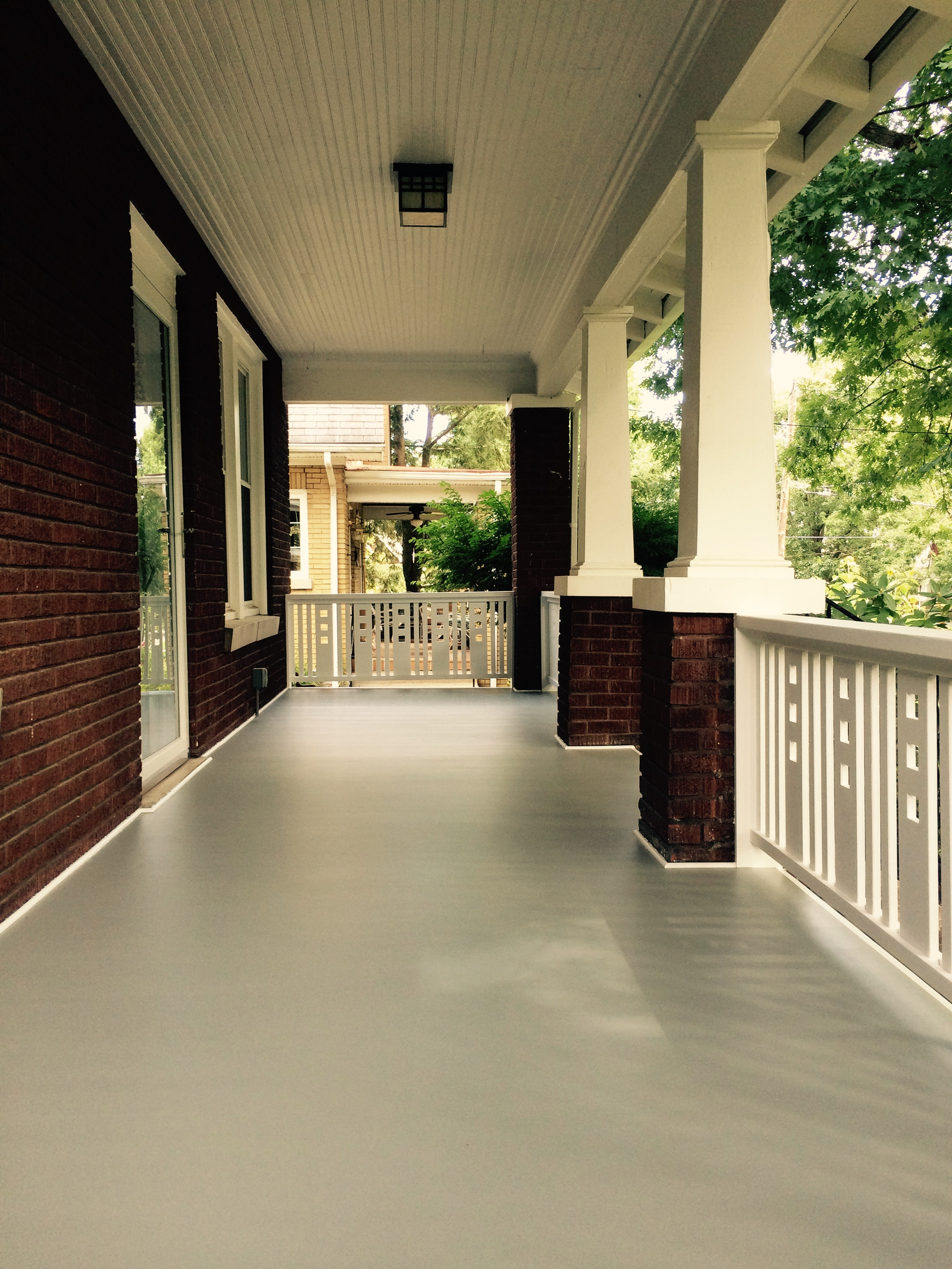A porch with a brick wall and a white railing
