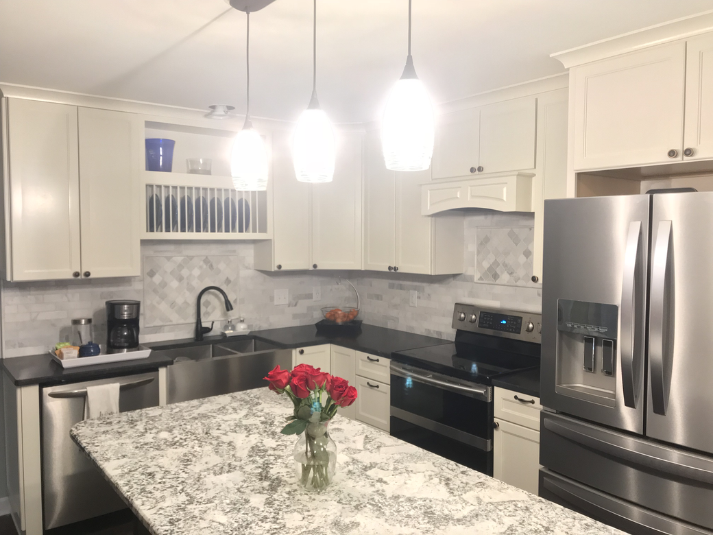 A kitchen with white cabinets , stainless steel appliances , granite counter tops and a stainless steel refrigerator.