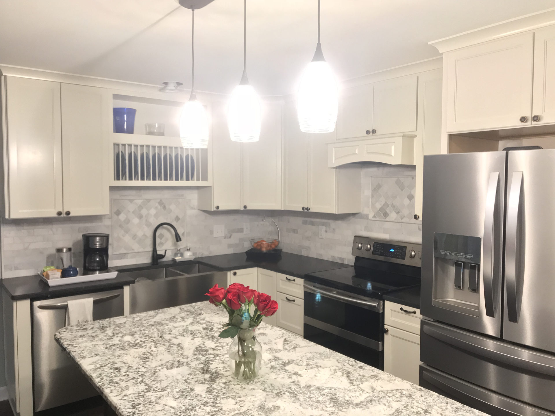A kitchen with white cabinets , stainless steel appliances , granite counter tops and a stainless steel refrigerator.