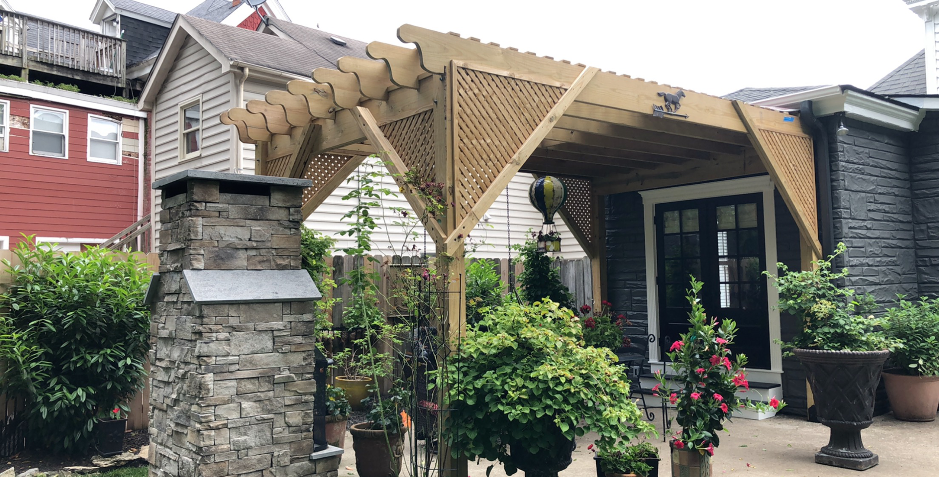 A wooden pergola is sitting in front of a house.