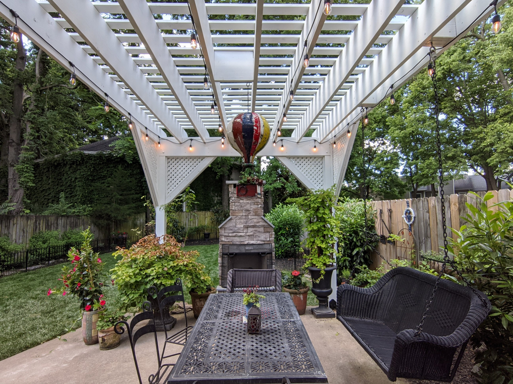 A patio with a table and chairs under a pergola with a hot air balloon hanging from the ceiling.