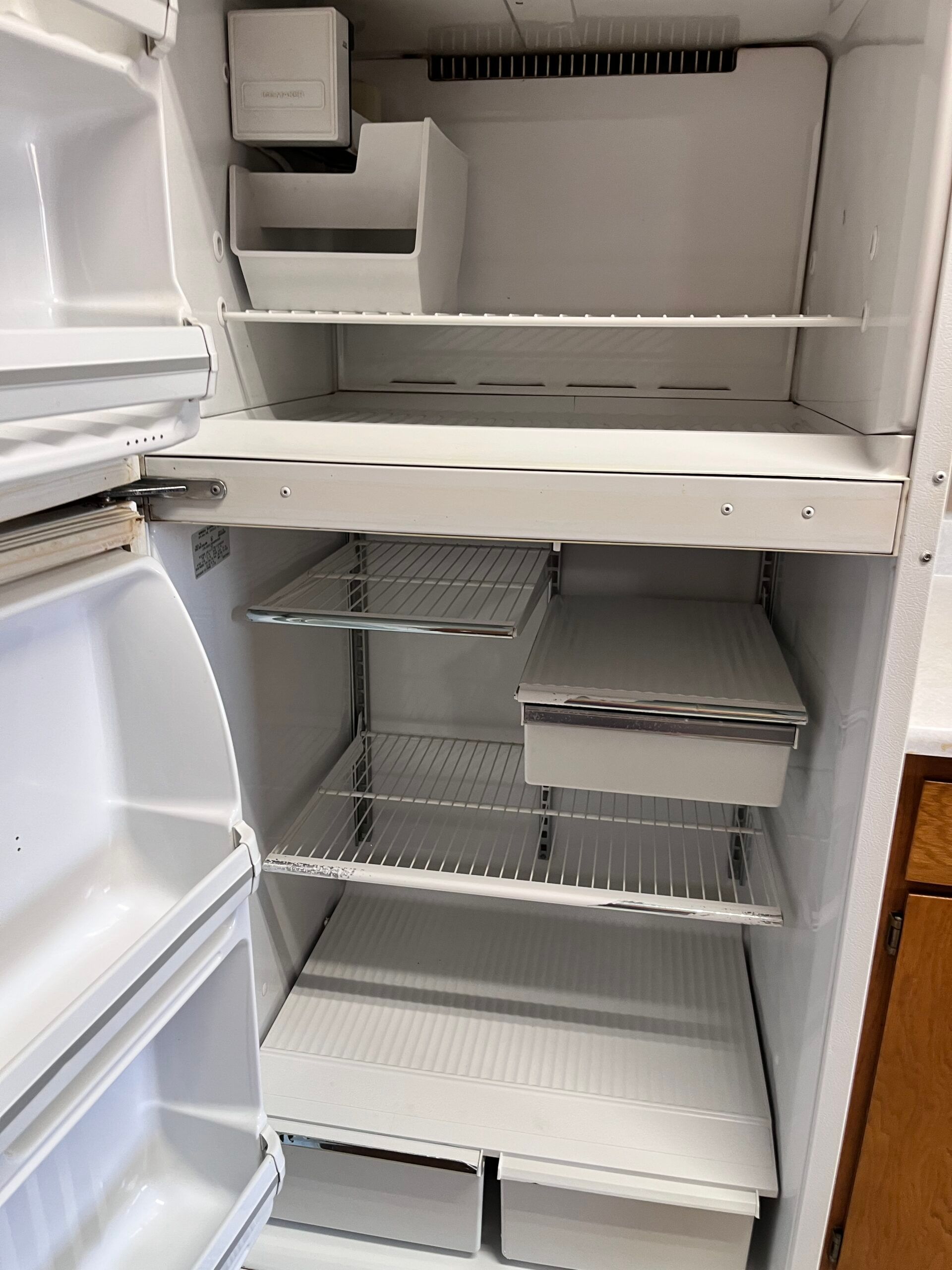 Empty white refrigerator interior with shelves and compartments.