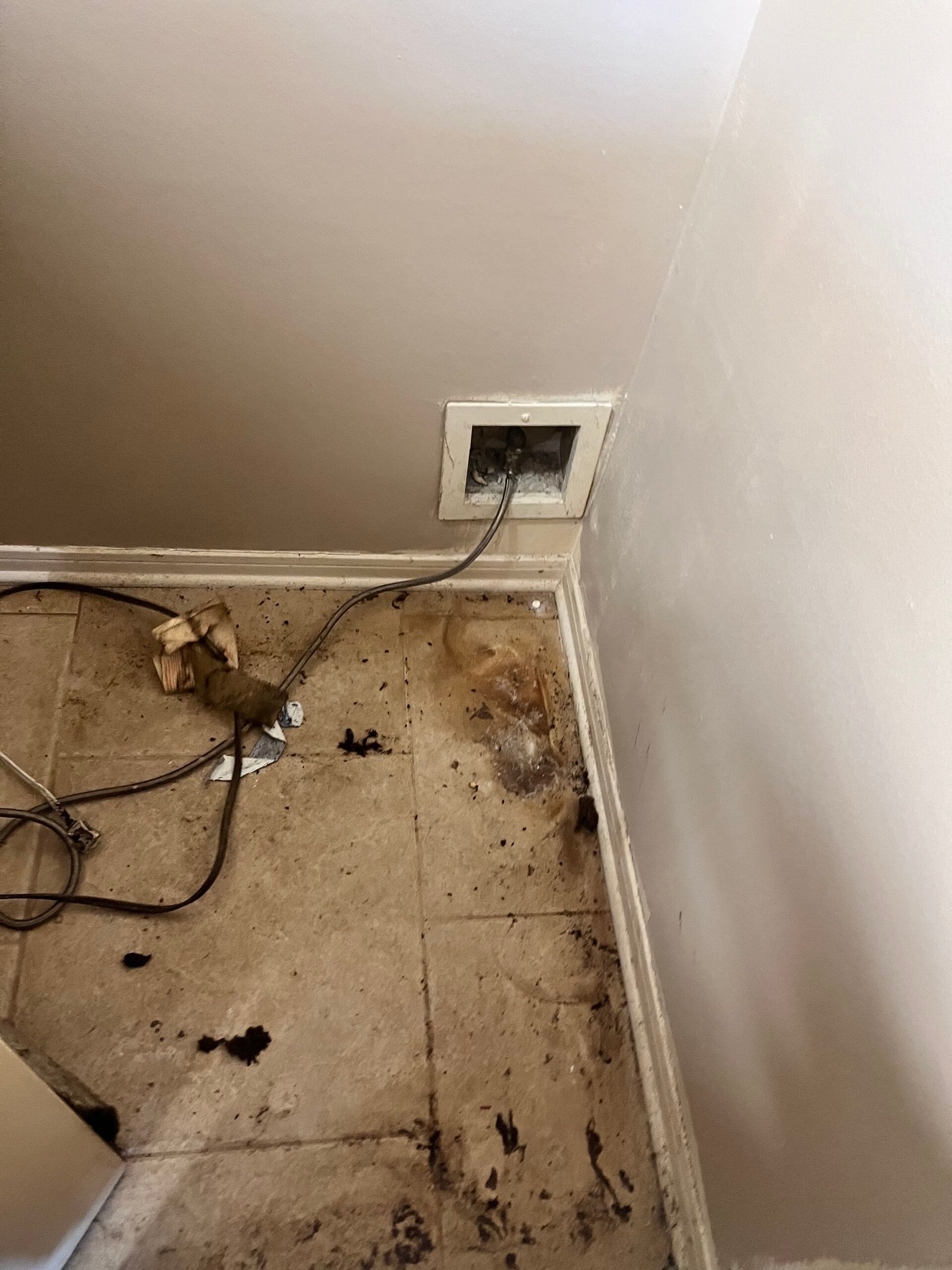 Air vent in ceiling with cables and stained floor, likely from water damage.