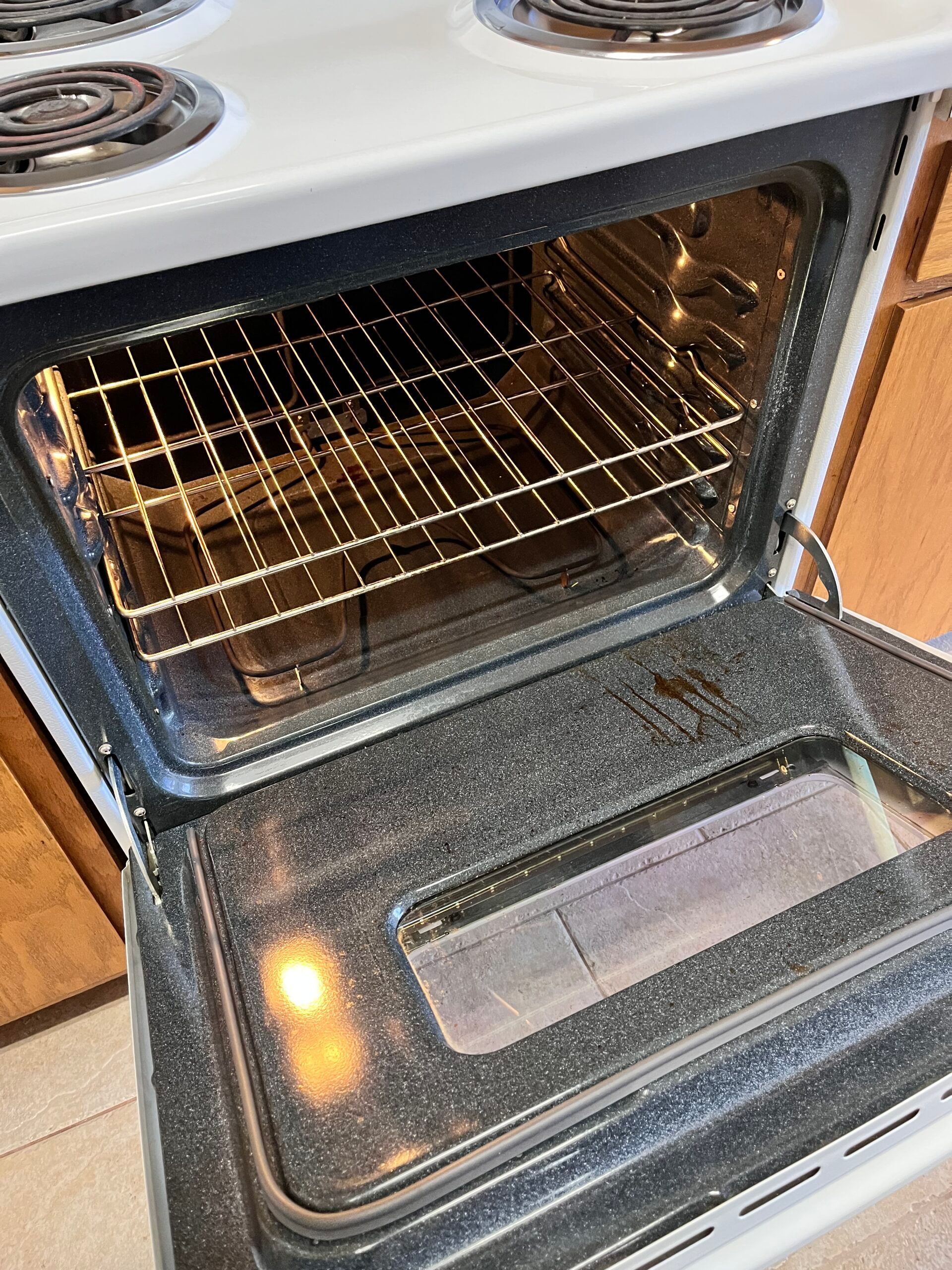 Open oven with racks inside, a black interior, and white door.