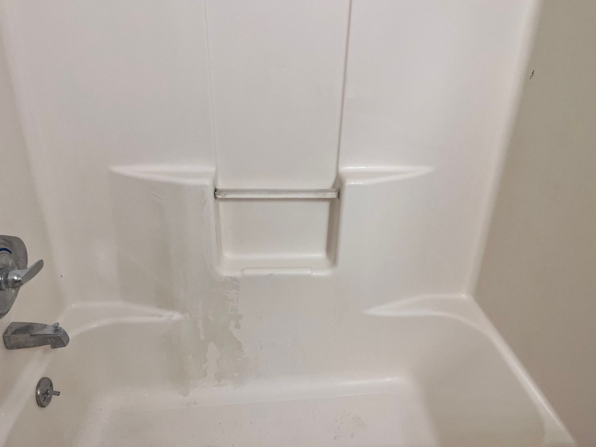 White bathtub with shower fixtures and soap shelf.