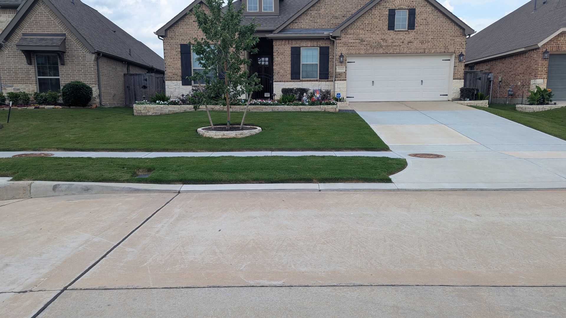 A brick house with a concrete driveway in front of it.