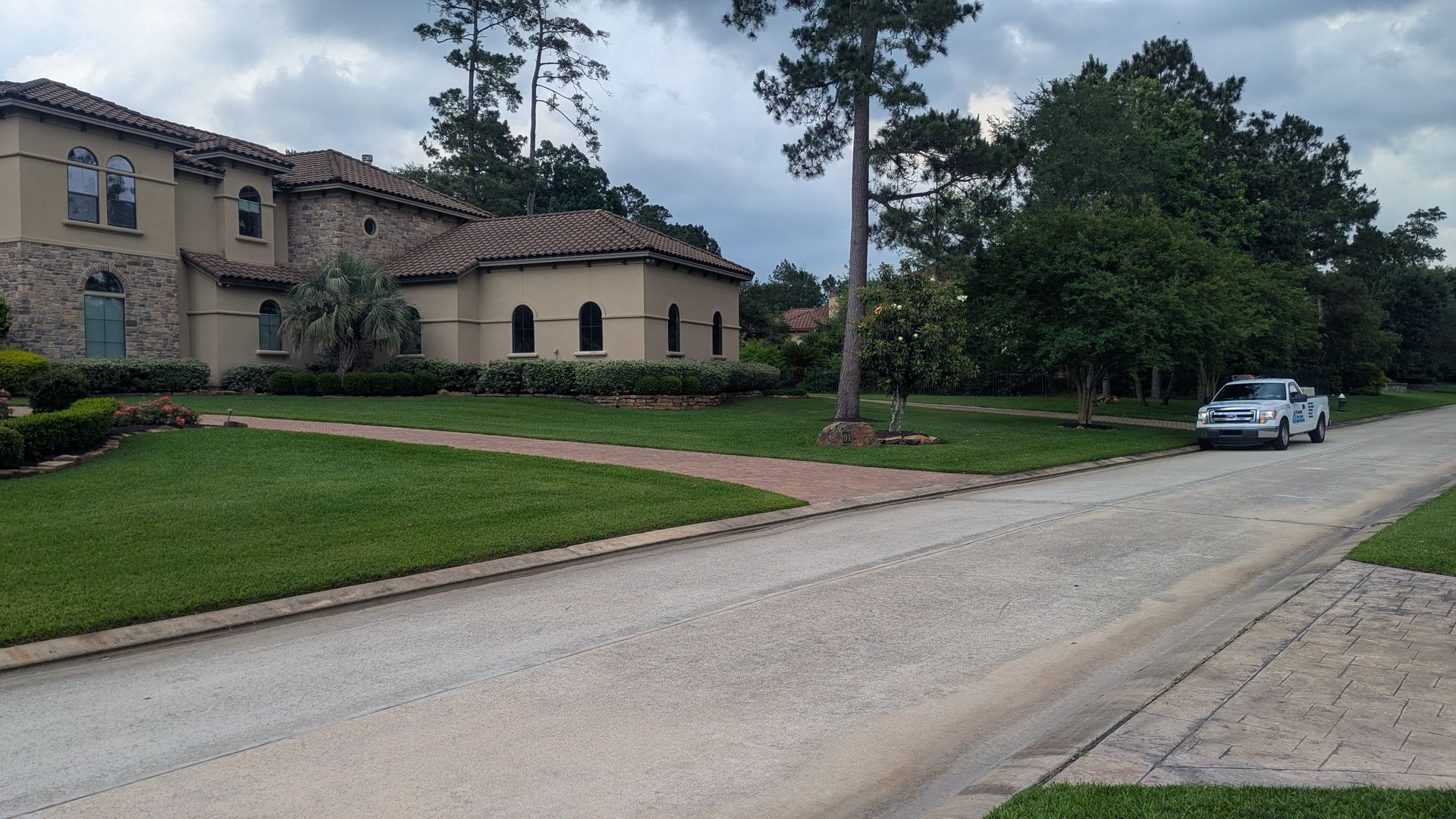 A car is parked on the side of the road in front of a large house