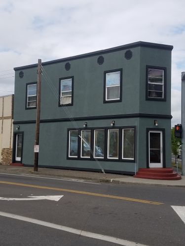 A large building with a lot of windows is on the corner of a street.