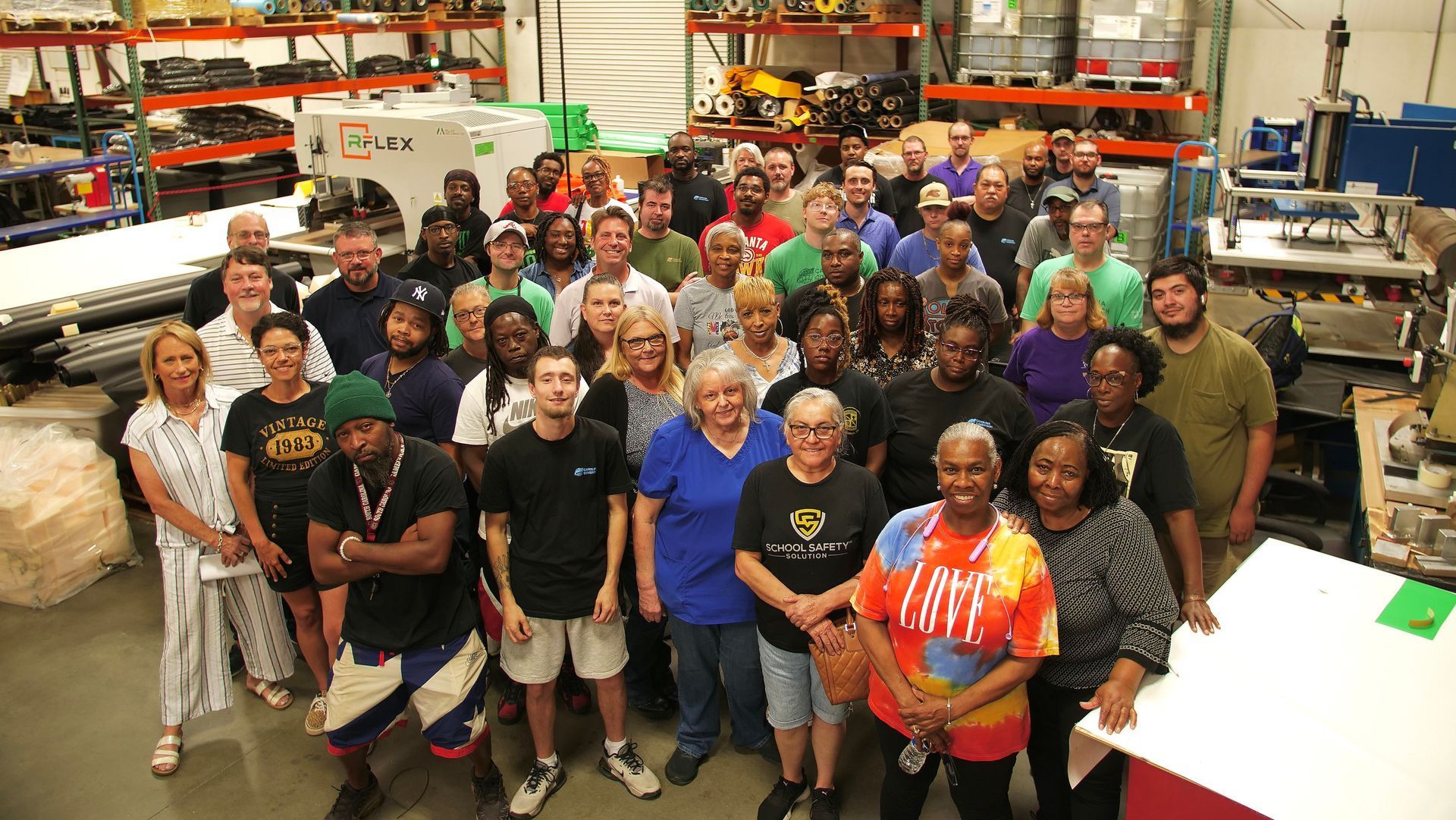 A large group of people are posing for a picture in a warehouse.