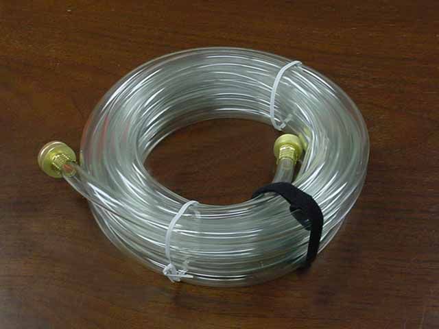 A clear hose with two brass fittings is sitting on a wooden table.