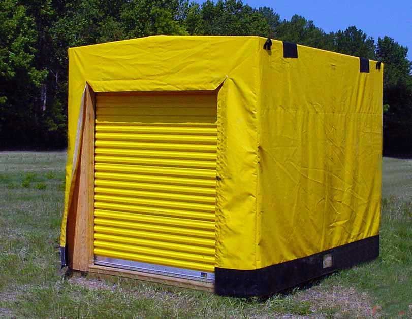 A yellow tarp is covering a garage door in a field