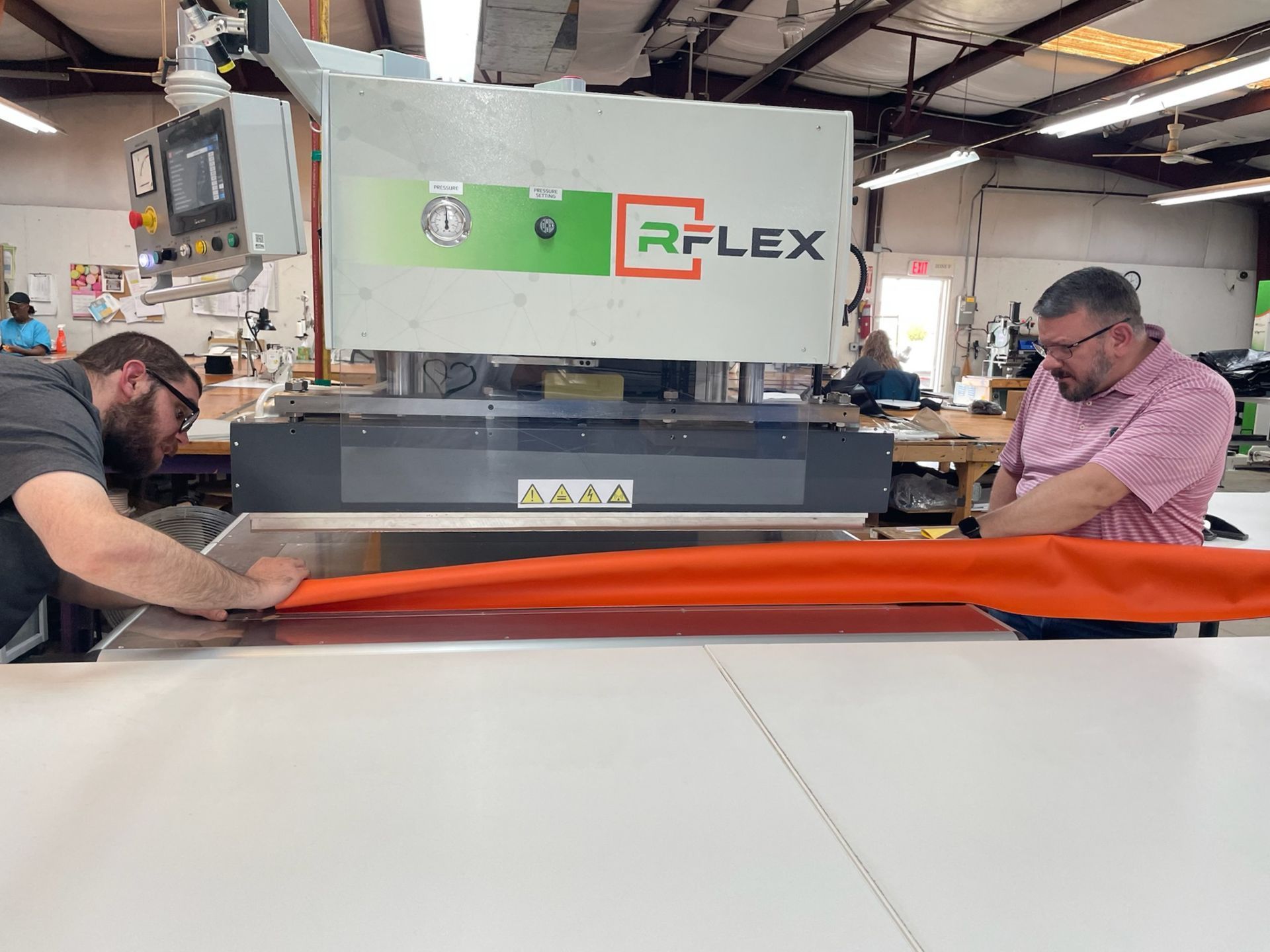 Two men are working on a machine to develop a product.