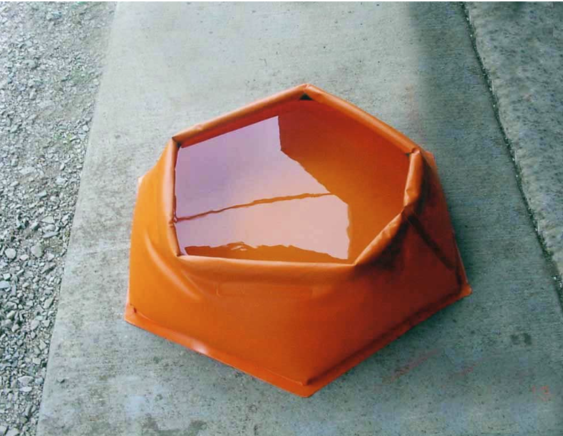 Orange, hexagon-shaped spill containment berm filled with liquid, sitting on concrete.