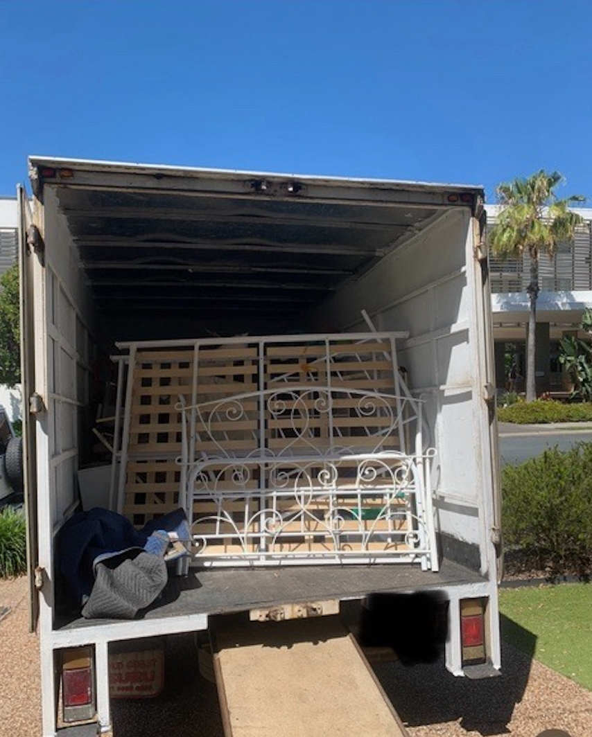 Back of a white moving truck loaded with a white metal bed frame and wooden slats, ready for transport — Rob's Rubbish Removal in Byron Bay, NSW
