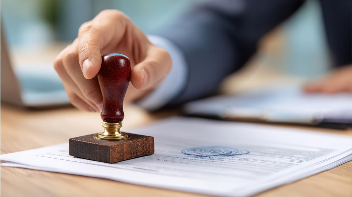 Hand stamping a document with a red wax seal on a desk