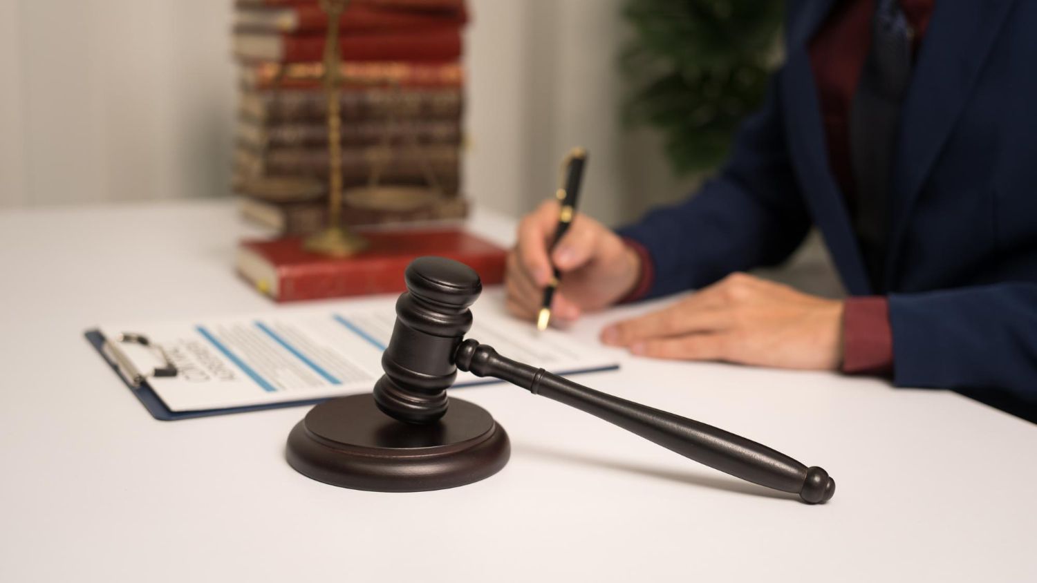 Judge’s gavel on desk beside person signing documents in an office