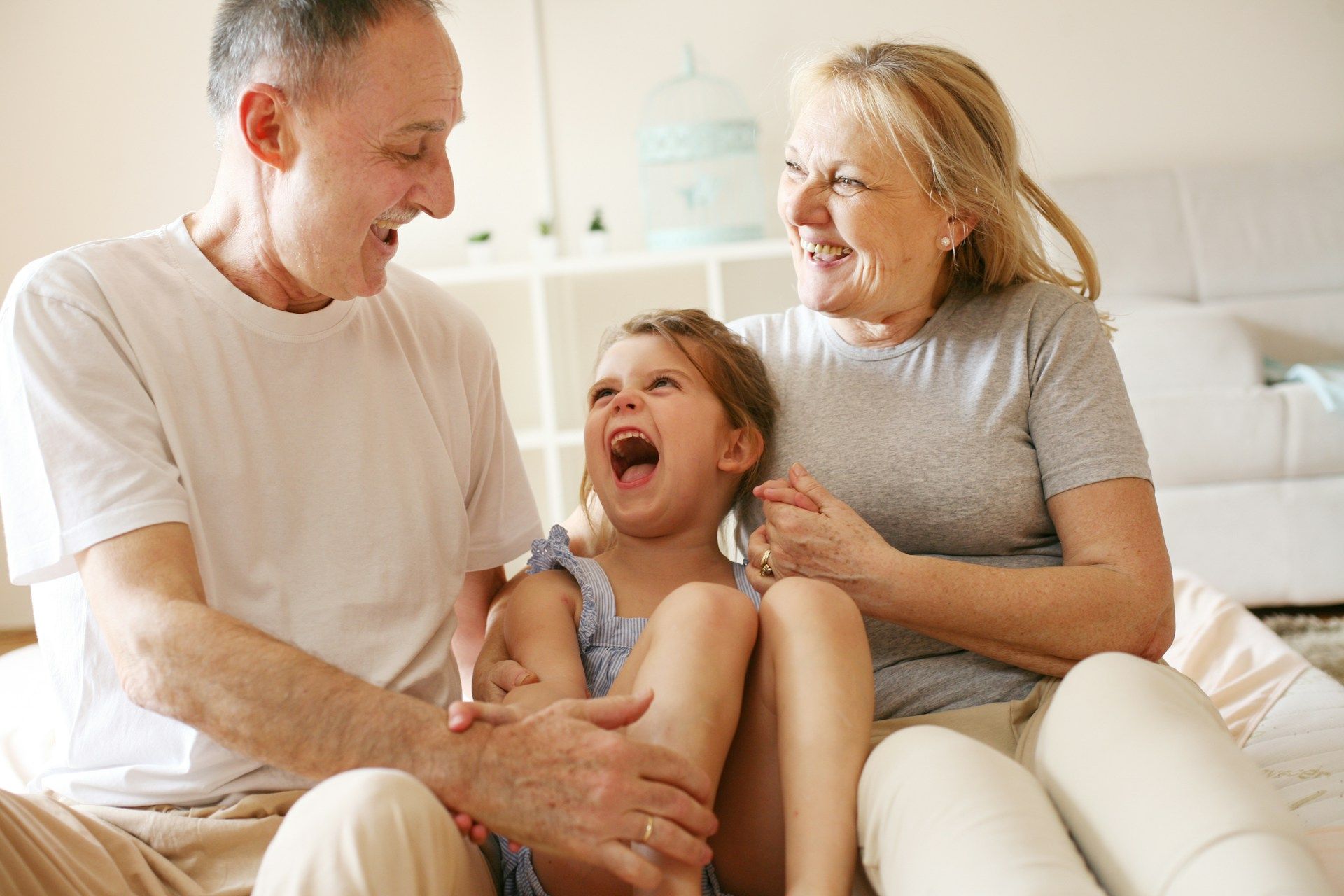 Smiling family sitting together on a couch, laughing in a bright living room