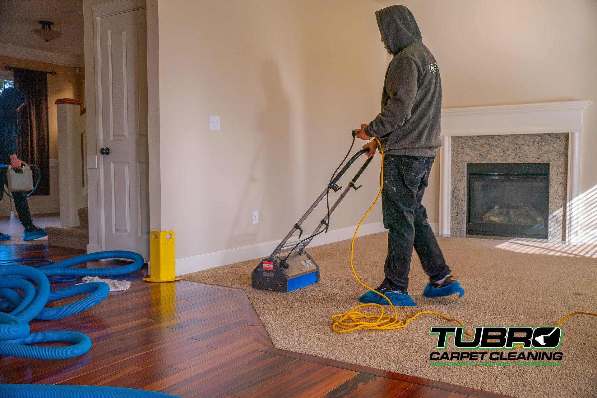 A man is cleaning a carpet in a living room with a vacuum cleaner.