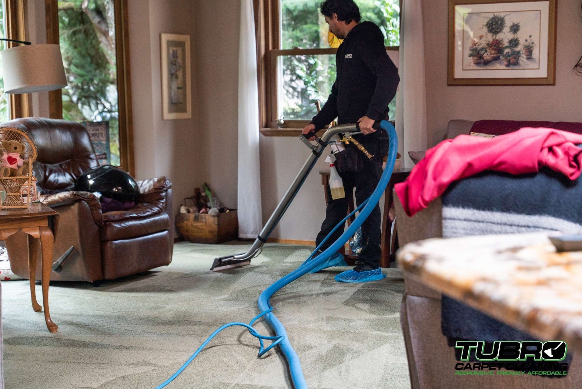 A man is using a vacuum cleaner to clean a carpet in a living room.
