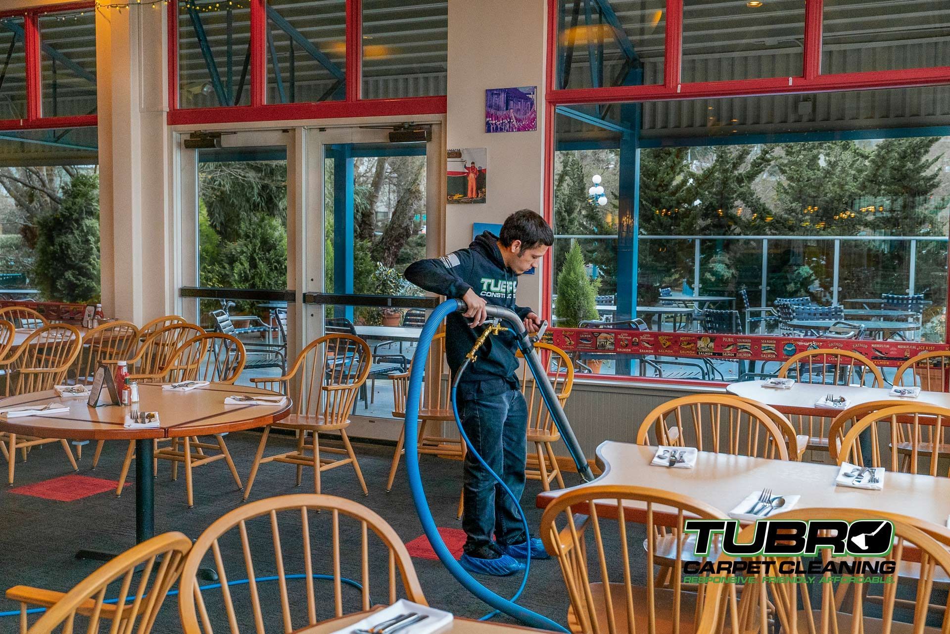 A man is cleaning a restaurant with a vacuum cleaner.