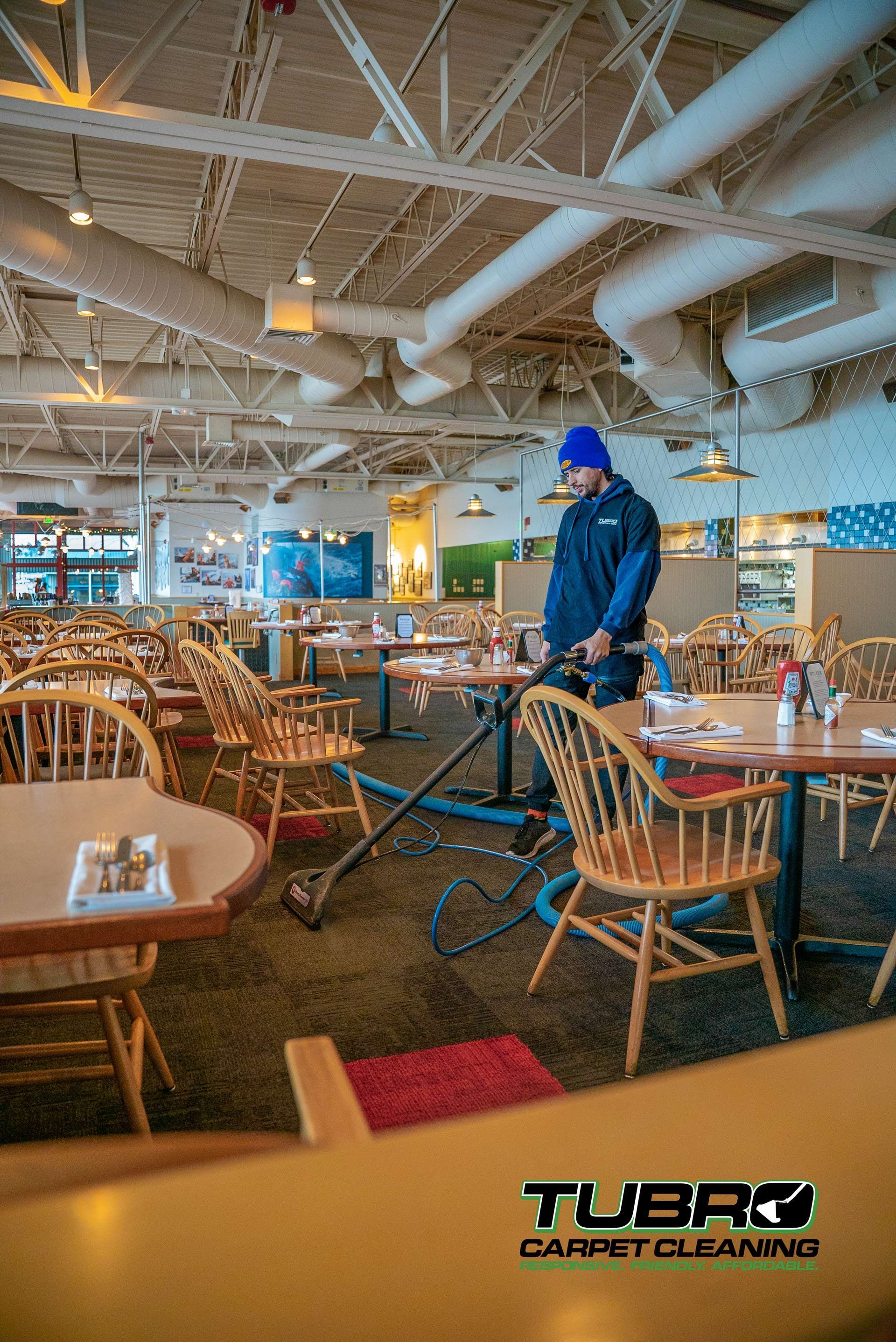 A man is cleaning a restaurant with a vacuum cleaner.