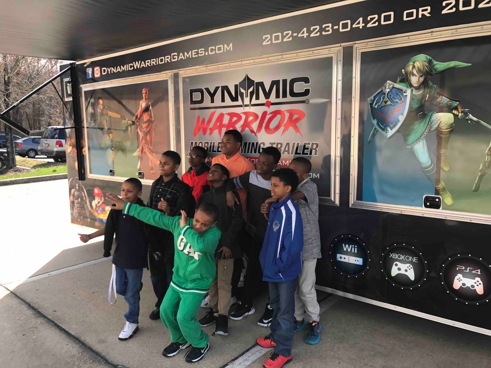 Group of children posing in front of a mobile gaming trailer. 