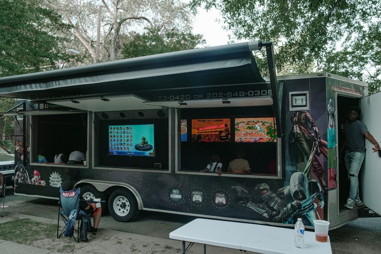 A gaming trailer with multiple screens displaying video games. A person stands in the doorway.