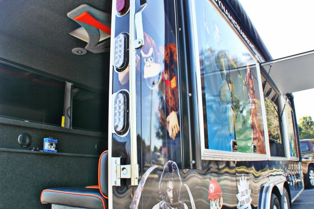 Food truck exterior with large windows displaying menu items; black and orange color scheme.