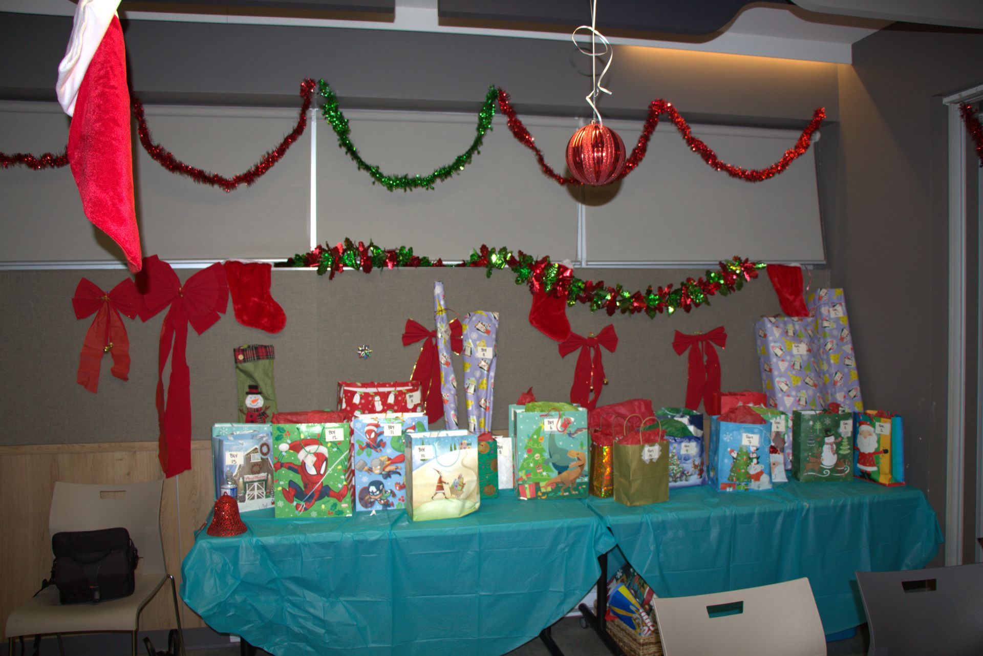 Christmas gifts on a teal table, decorated with garland, bows, and a stocking.