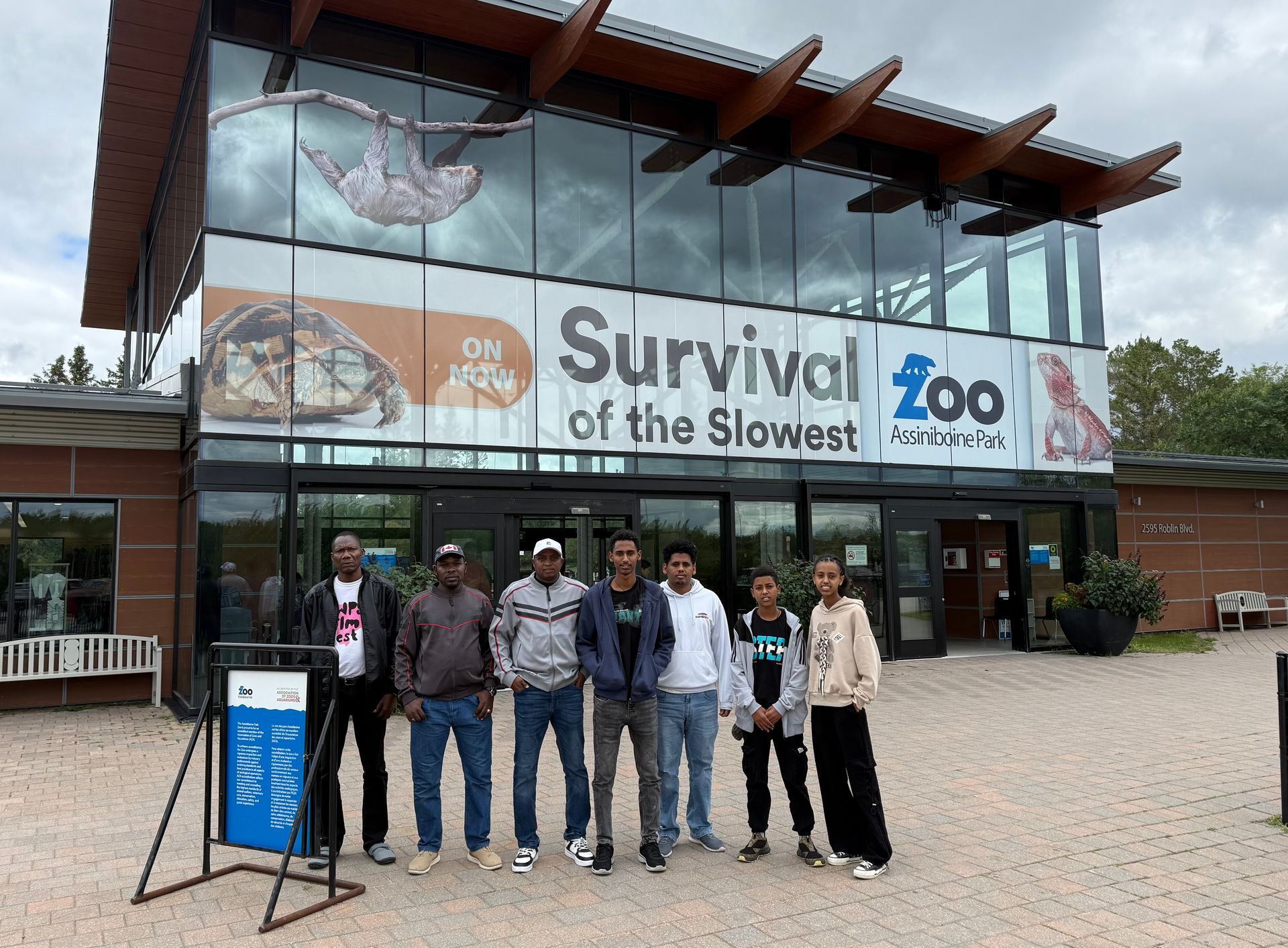 Group of people posing in front of a zoo entrance that reads