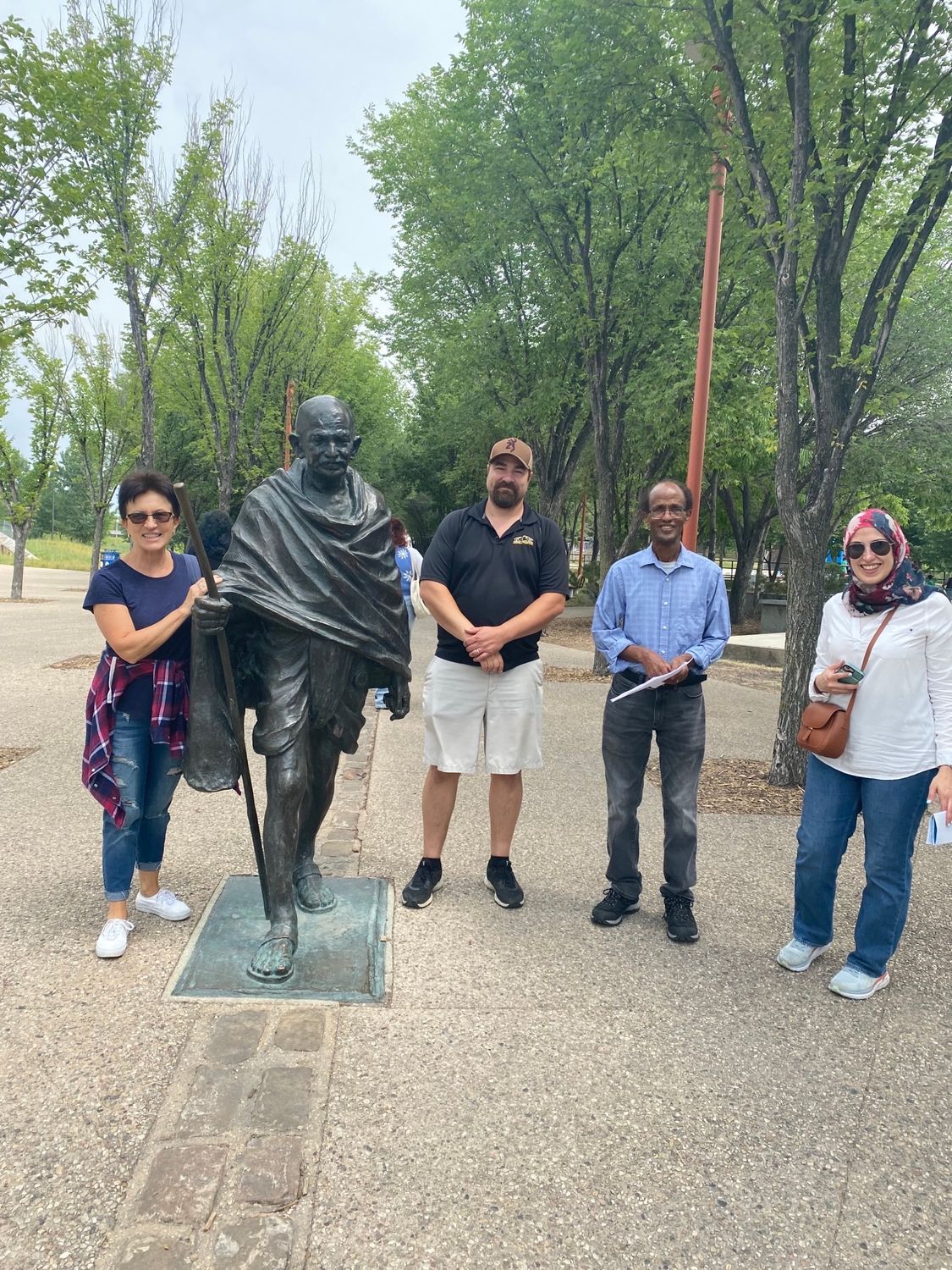 A group of people are standing in front of a statue of mahatma gandhi.