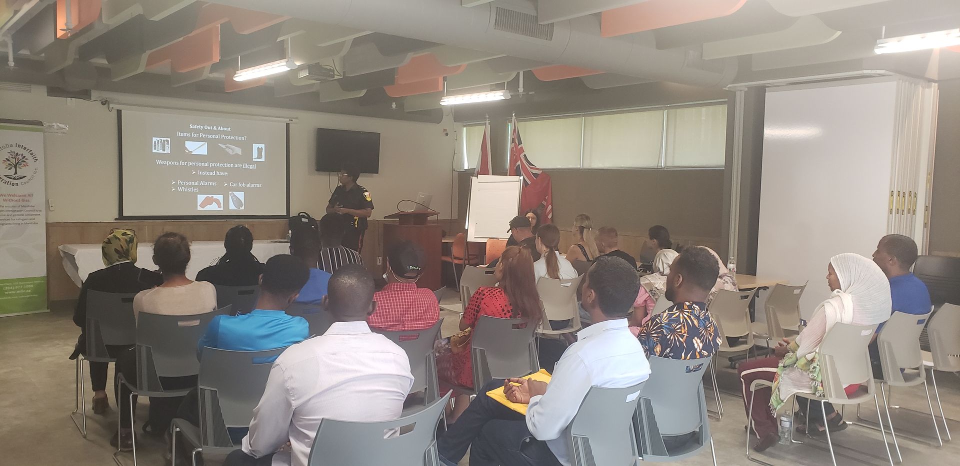 A group of people are sitting in chairs in front of a projector screen.