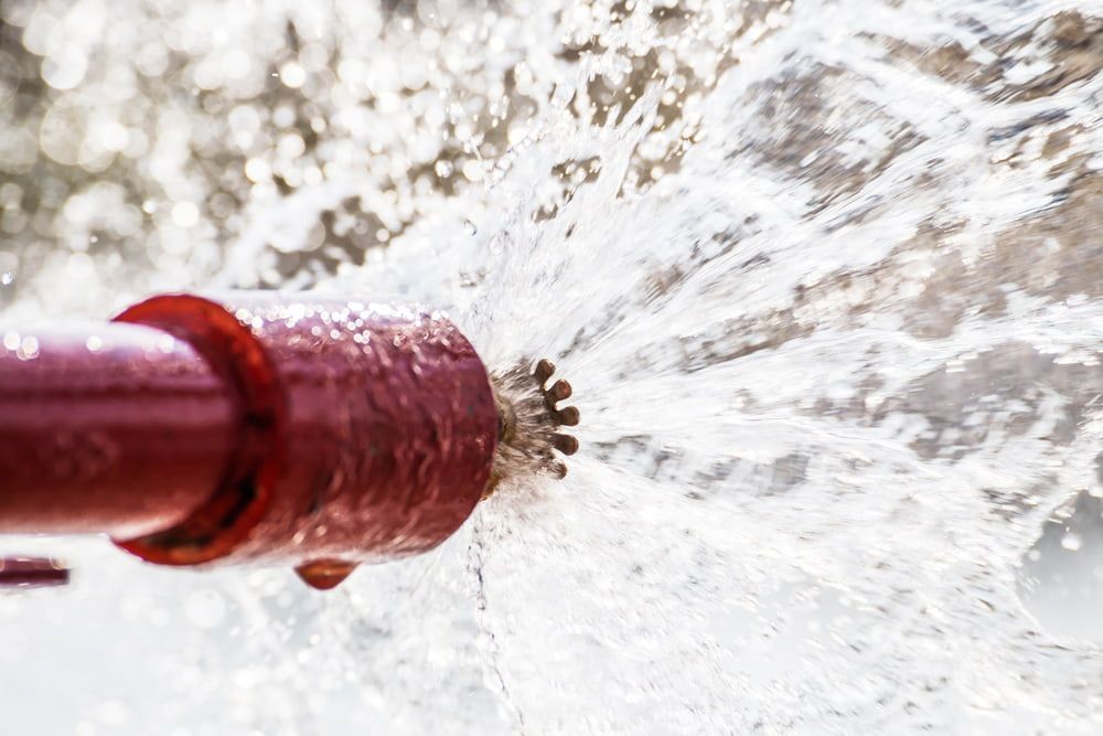 A Fire Sprinkler is Spraying Water From a Red Pipe — East-West Fire Services In Cloncurry, QLD