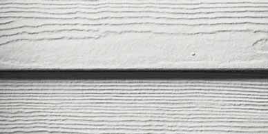 Close-up of white siding with horizontal, textured lines and a dark shadow.