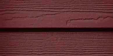 Close-up of red-brown horizontal wood siding, showing texture and a dark line between boards.
