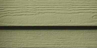Close-up of green lap siding with horizontal lines and a dark shadow between boards.