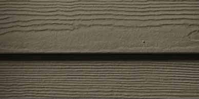 Close-up of horizontal, textured, brown siding with a dark shadow separating the panels.