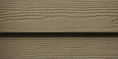 Close-up of light brown siding with horizontal wood grain lines.