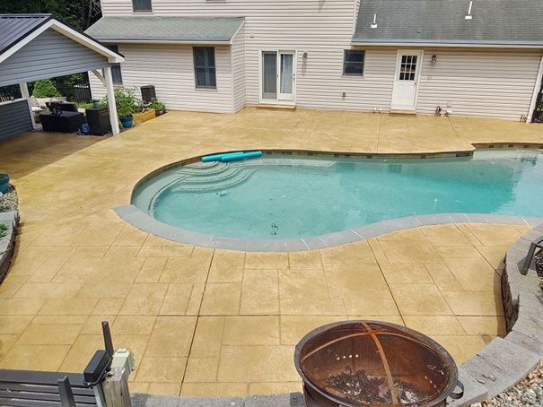 Backyard with pool and stamped concrete patio, a fire pit, and a covered area near the house.