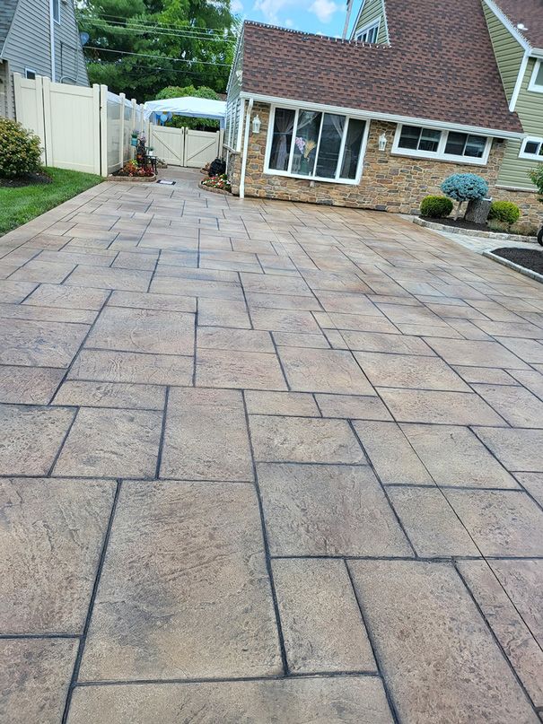 Stamped concrete driveway leading to a brick house, featuring brown and gray rectangular patterns.