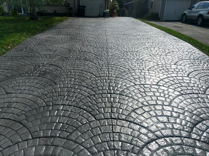 Gray cobblestone-patterned concrete driveway leading toward a garage.