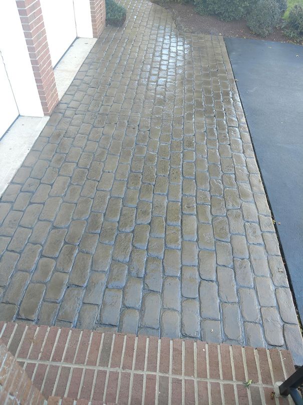 Brick paved walkway with a brick border next to a black driveway.