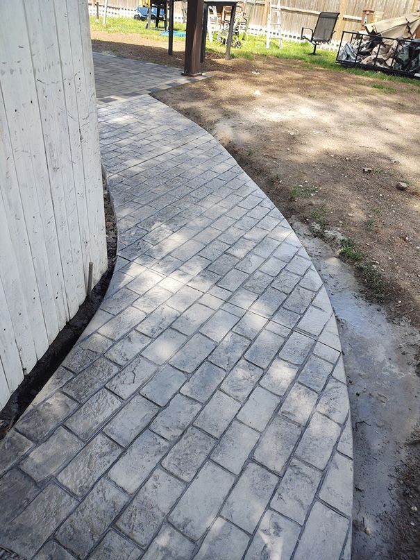 Curved brick pathway next to a white wall.