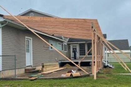 framing1 Construction of an outdoor porch addition to a house; wood framing, brown roof, beige siding.