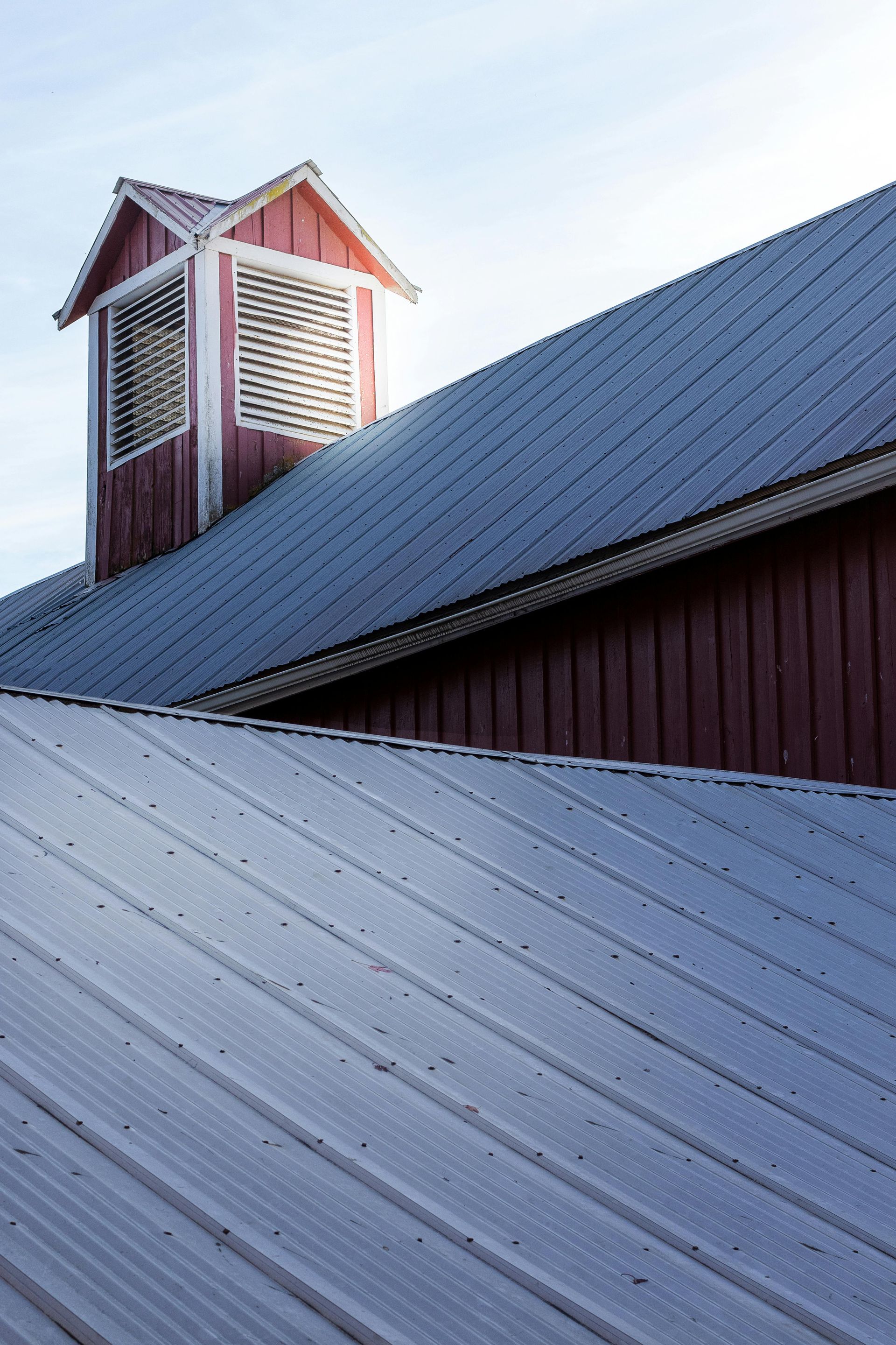 Red barn with a red metal roof, highlighting metal roofing benefits and durability
